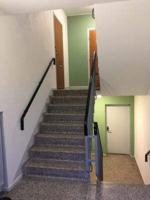 Trapphus med trappa upp till ett par lägenhetsdörrar och ner till en källardörr
