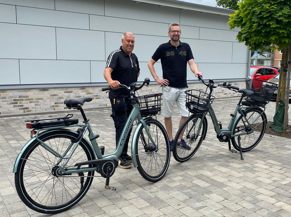 Två män står och håller i styret på två elcyklar.