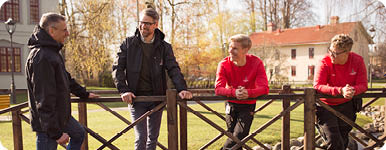 Fyra personer står och samtalar ute i en park