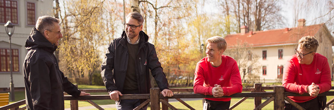 Fyra personer står och samtalar ute i en park